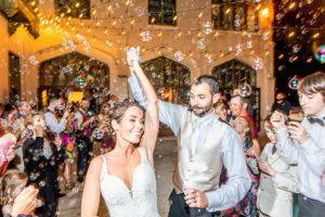 bride and groom standing on a terrace with bubbles at night