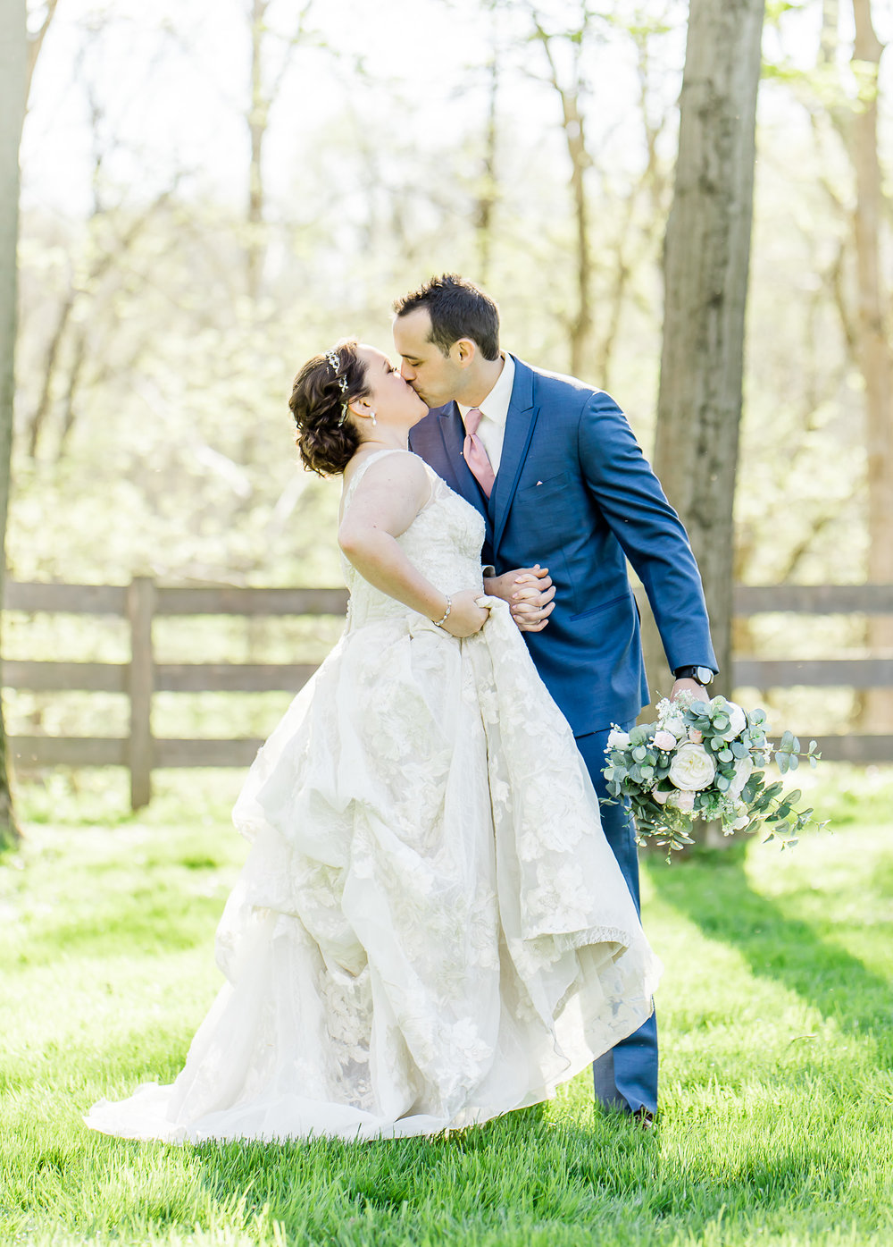 couple standing in a field kissing on their wedding day