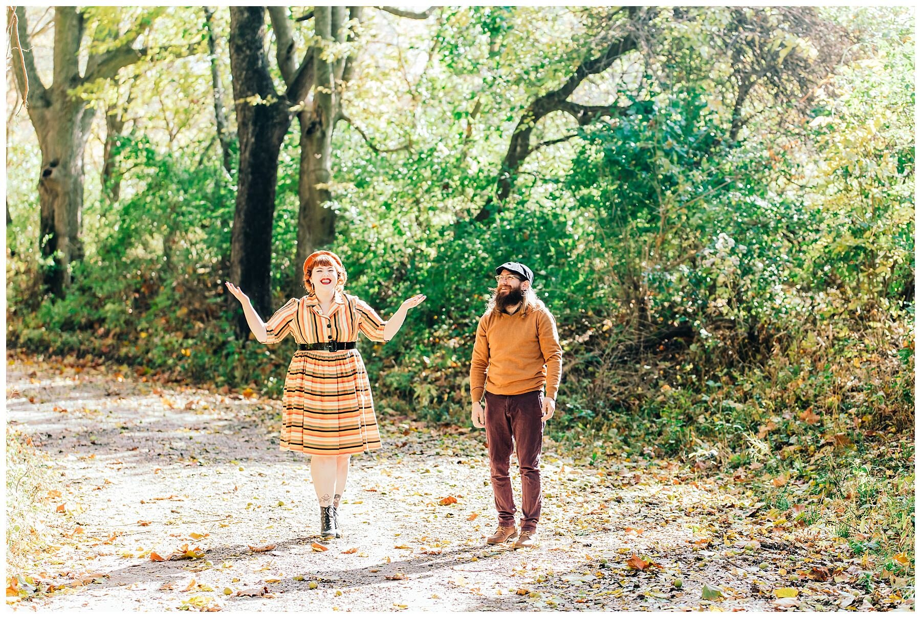 couple playing in the leaves in the fall on a road