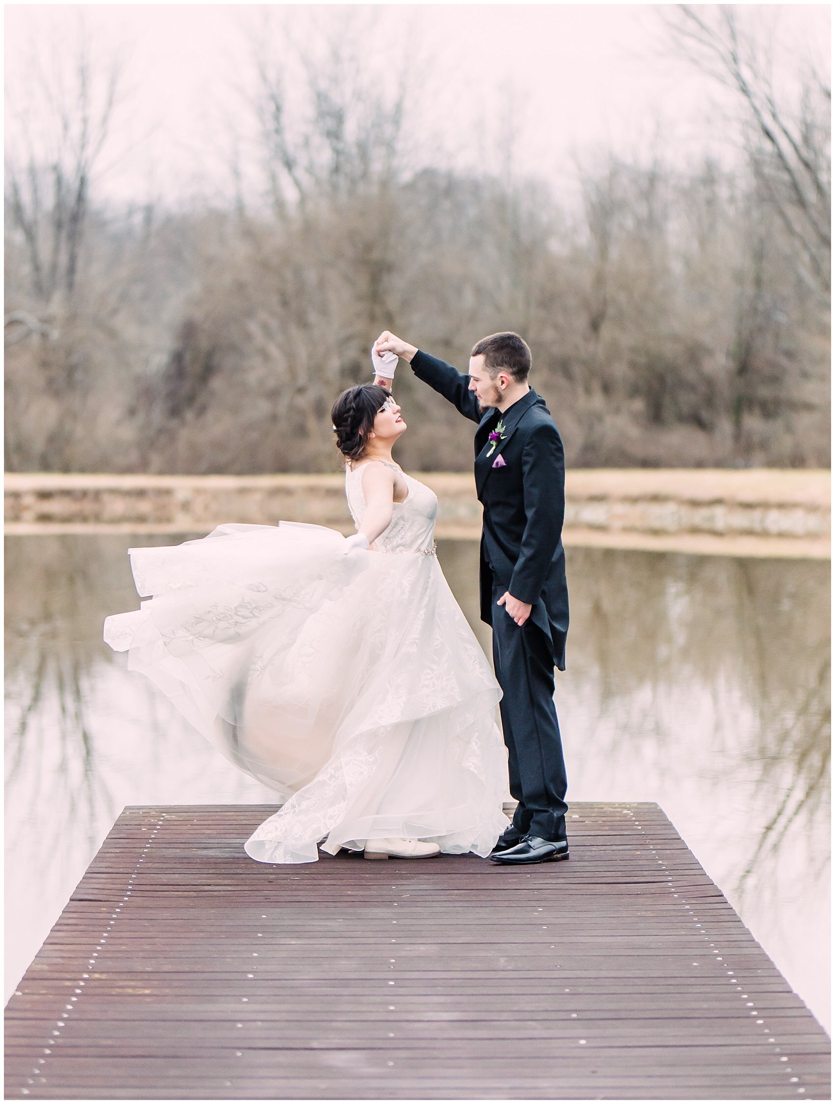 bride and groom standing on a dock twirling and throwing her dress 