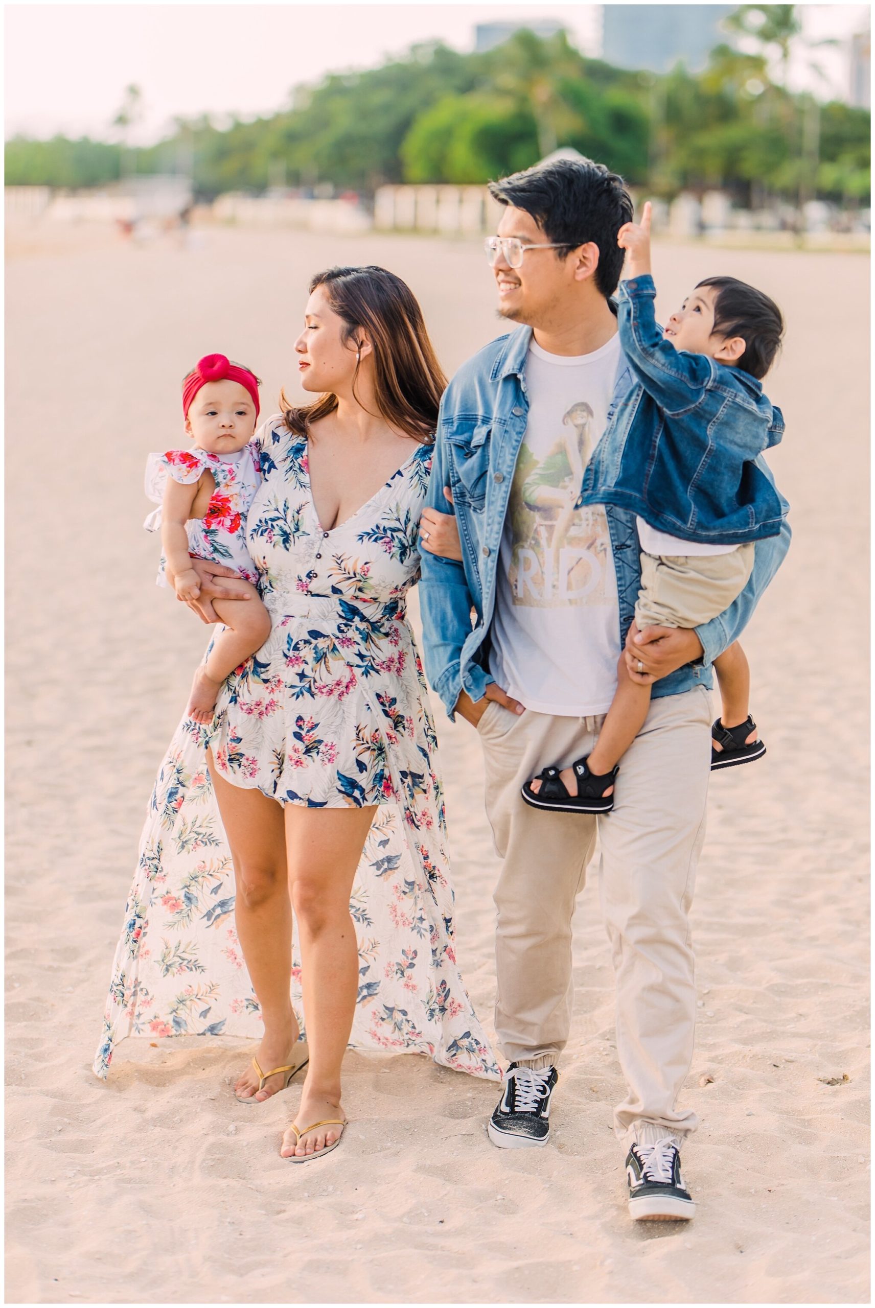 couple with two children walk together on a beach in hawaii 