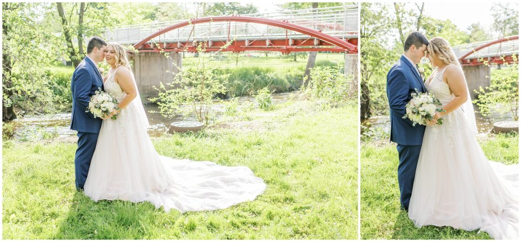 bride and groom standing in a park with a bridge in the background
