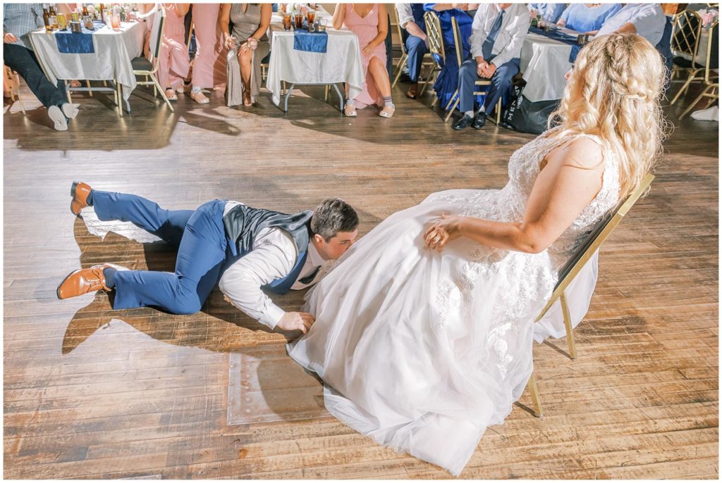 groom retrieving the garter under bride's dress