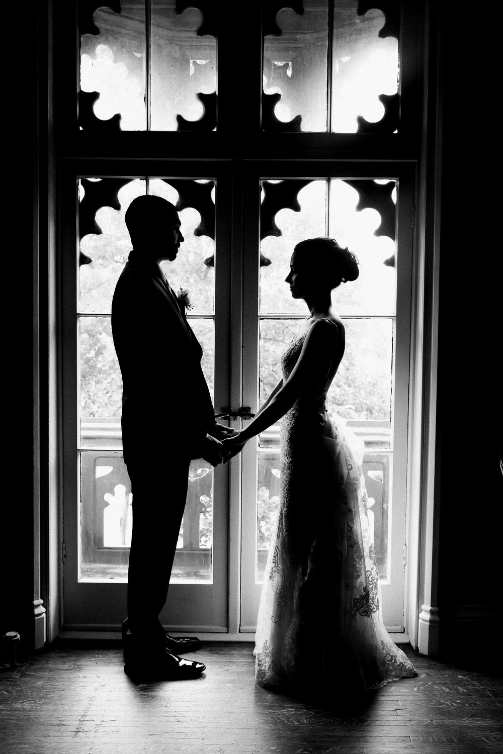 couple silhouetted in front of a window in their wedding clothes