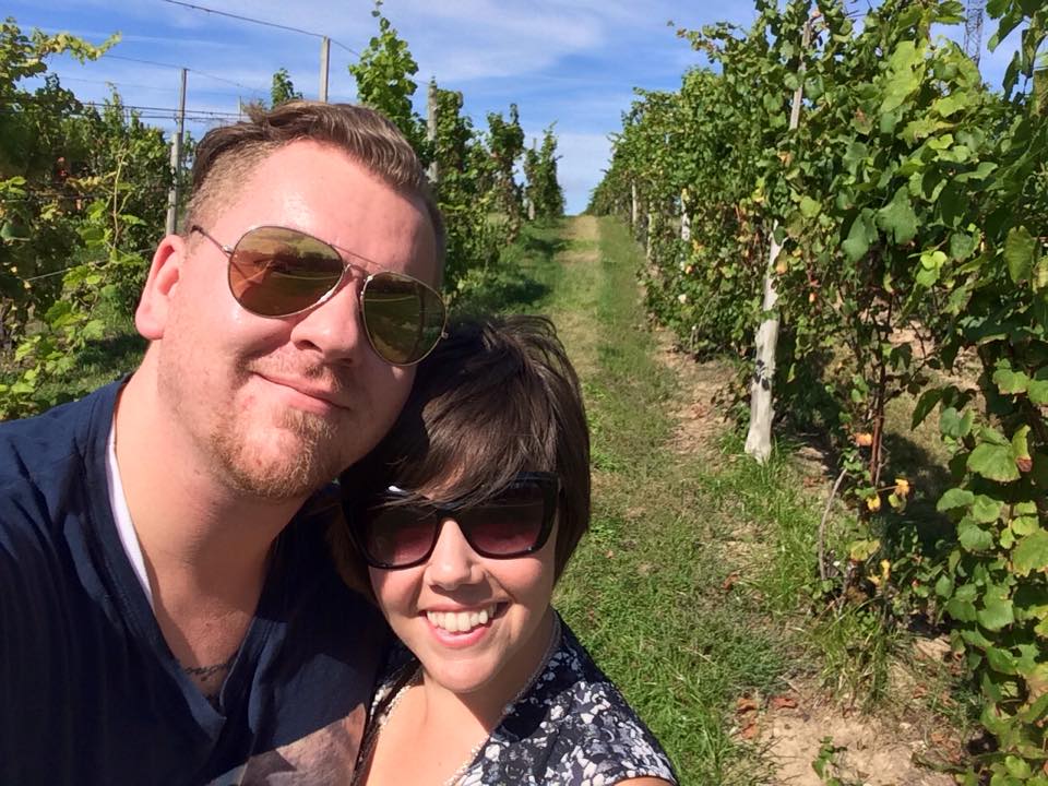 a man and woman taking a selfie at a winery in a vinyard