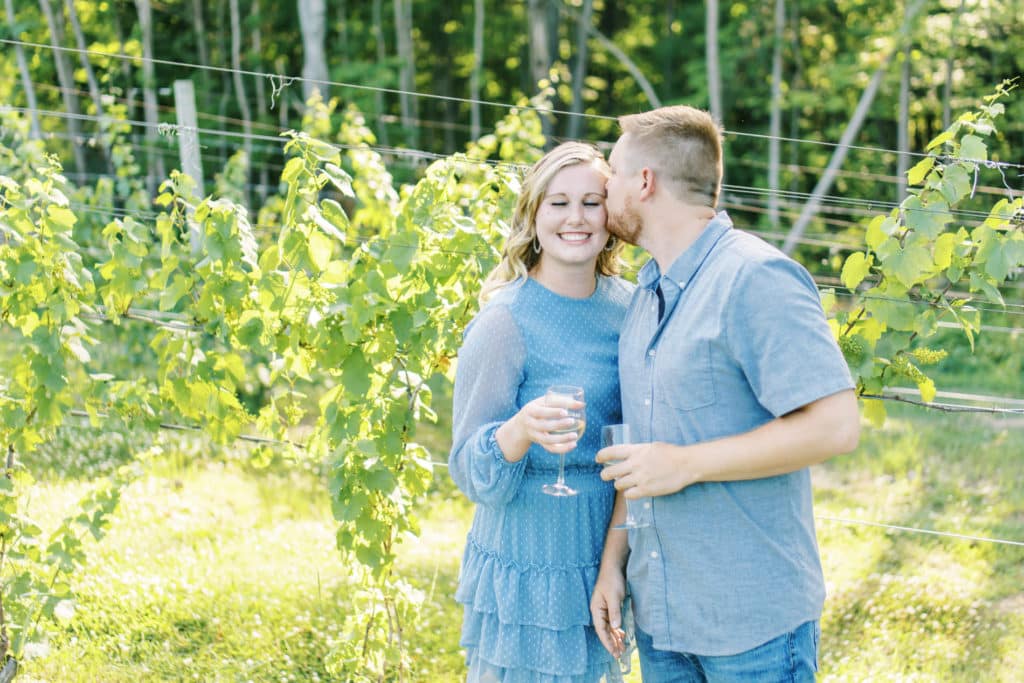 couple kissing at tabor hill winery in vineyard