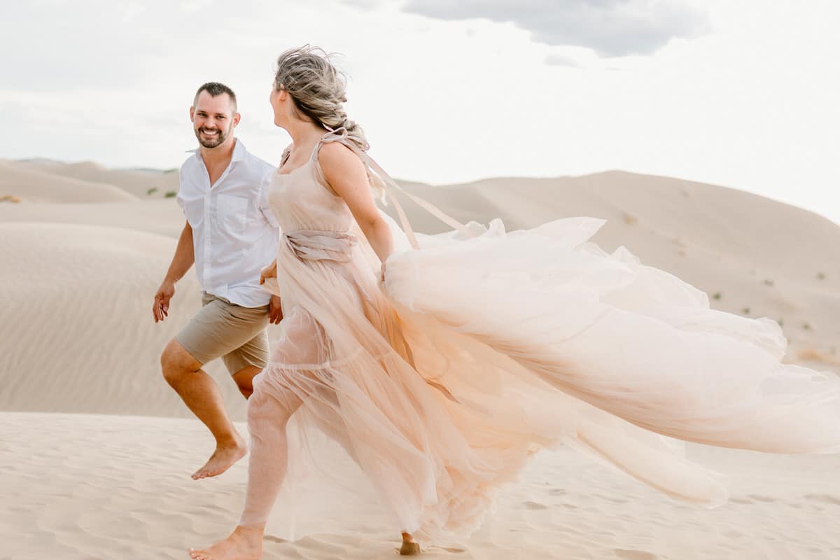 couple running on sand dunes